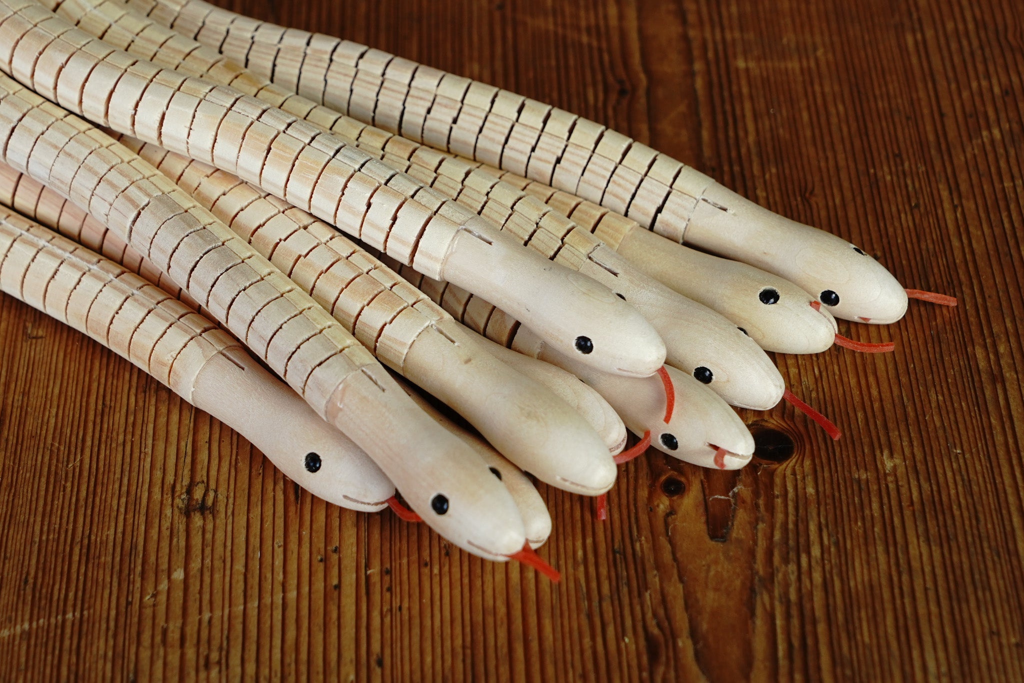 A bunch of wooden snakes, all unpainted.